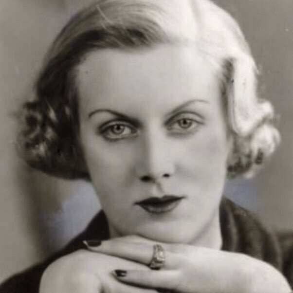 Un portrait en noir et blanc d'une femme avec des cheveux blonds bouclés et de fins sourcils.