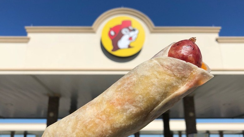 Saucisse enroulée devant le panneau Buc-ee's