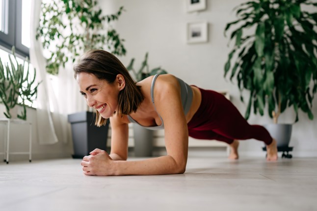 Femme souriante faisant un exercice de planche à la maison
