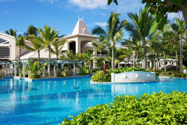La piscine principale du Sugar Beach, Maurice, entourée de verdure et de palmiers.