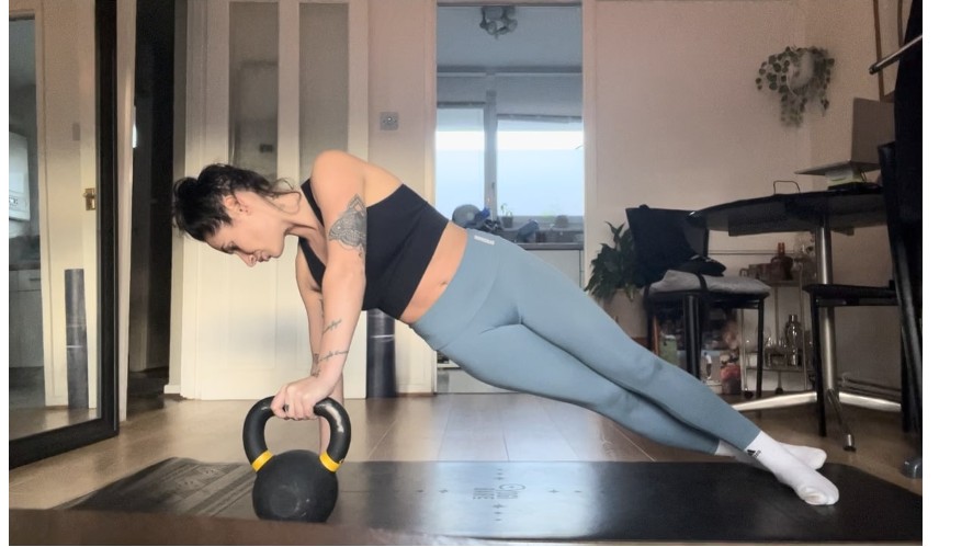 Une personne effectuant une rotation de planche avec un kettlebell