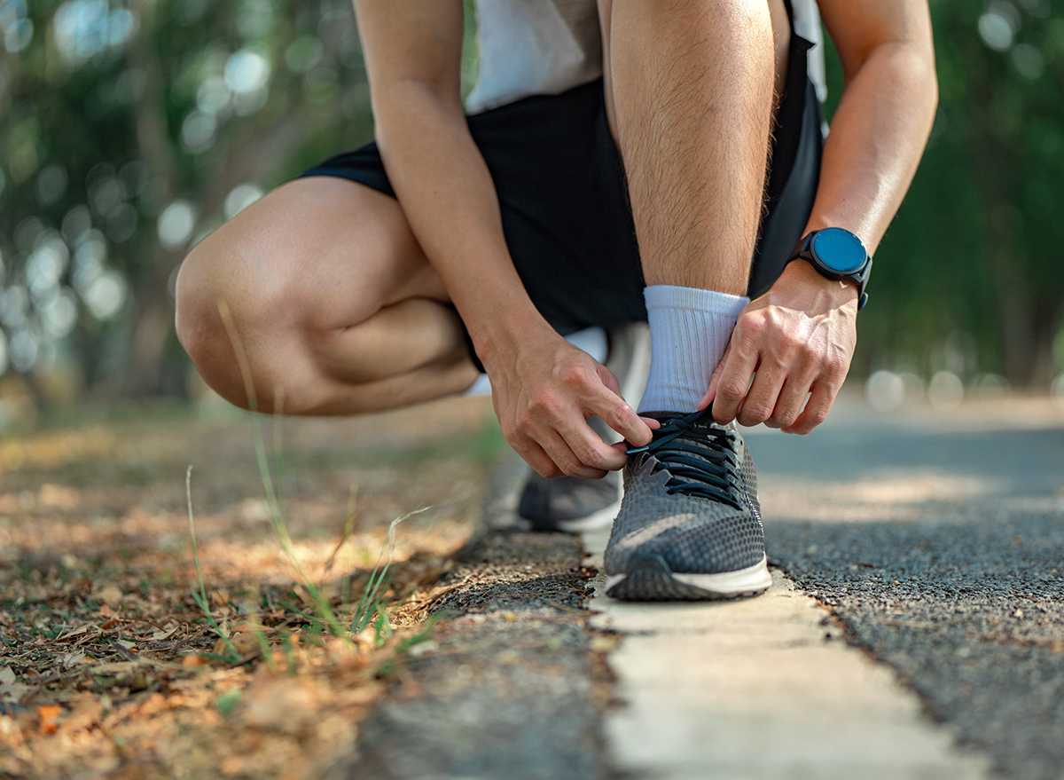 Homme attachant ses lacets pour une course en été. Motivation à l'exercice.