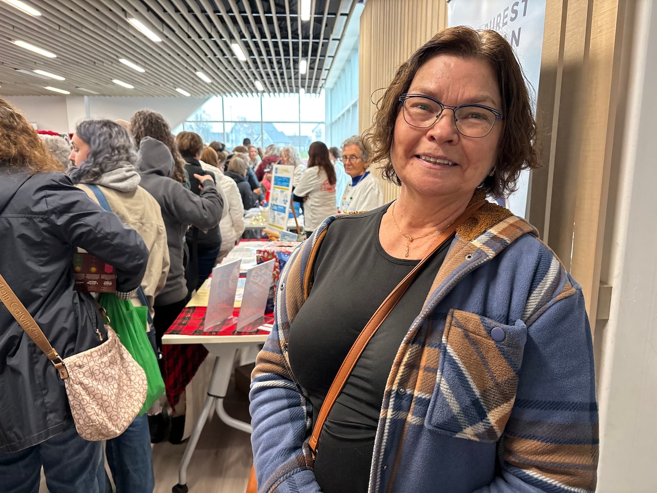 Une femme en manteau à carreaux se tient devant une table de produits sans gluten