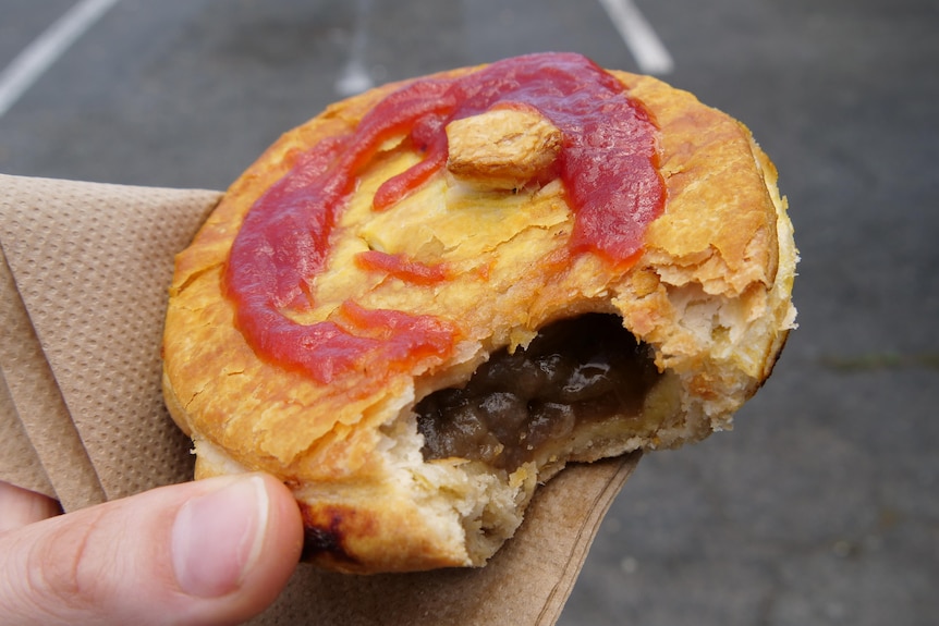 Une tarte dorée avec une bouchée prise, montrant la viande à l'intérieur.