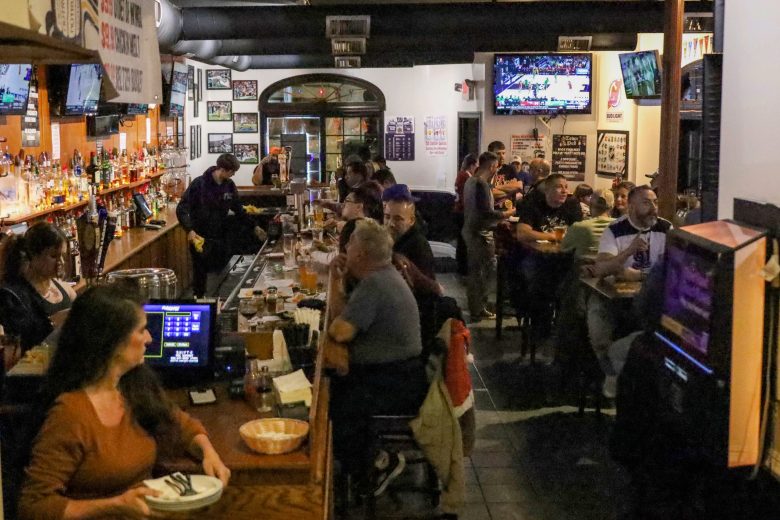 Clients discutant tout en dégustant de la nourriture et des boissons au Town Pub à Bloomfield, New Jersey. Ce pub est apprécié car il propose des événements sportifs et une cuisine décontractée depuis 1893.