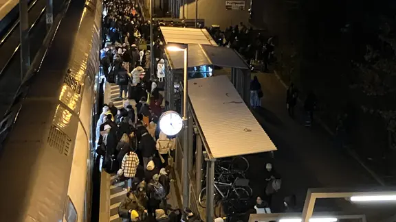 Un quai avec de nombreuses personnes devant un train.