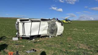 Photographie du véhicule accidenté, avec un hélicoptère médical visible en arrière-plan.