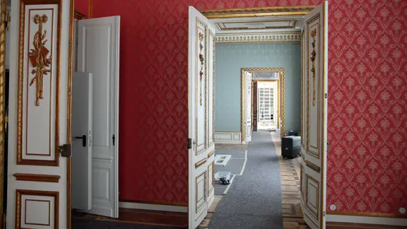 Une porte ouverte dans une pièce du château, permettant de voir dans la pièce suivante.