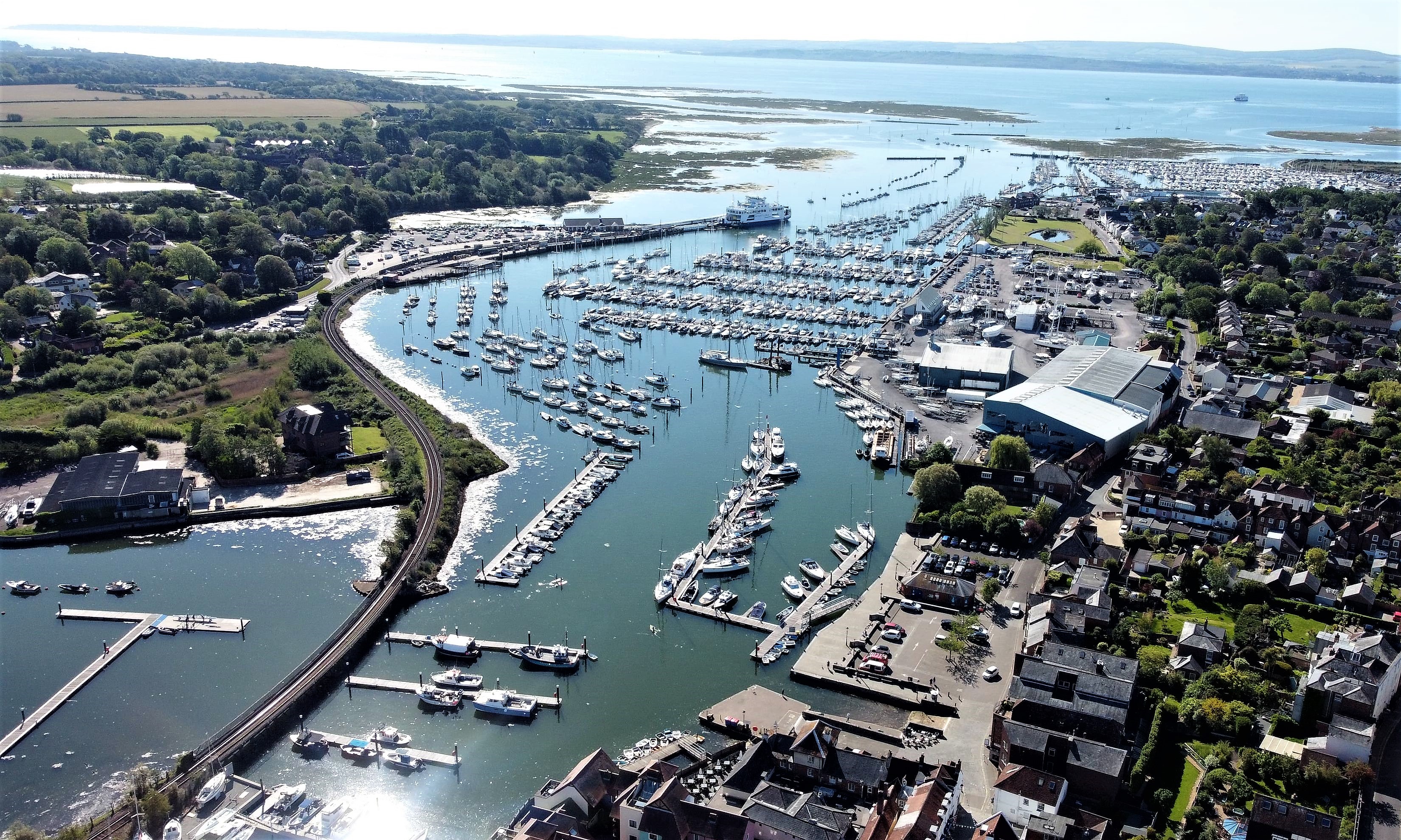 Vue aérienne du port de Lymington, montrant des yachts à quai et le marais salant en arrière-plan.