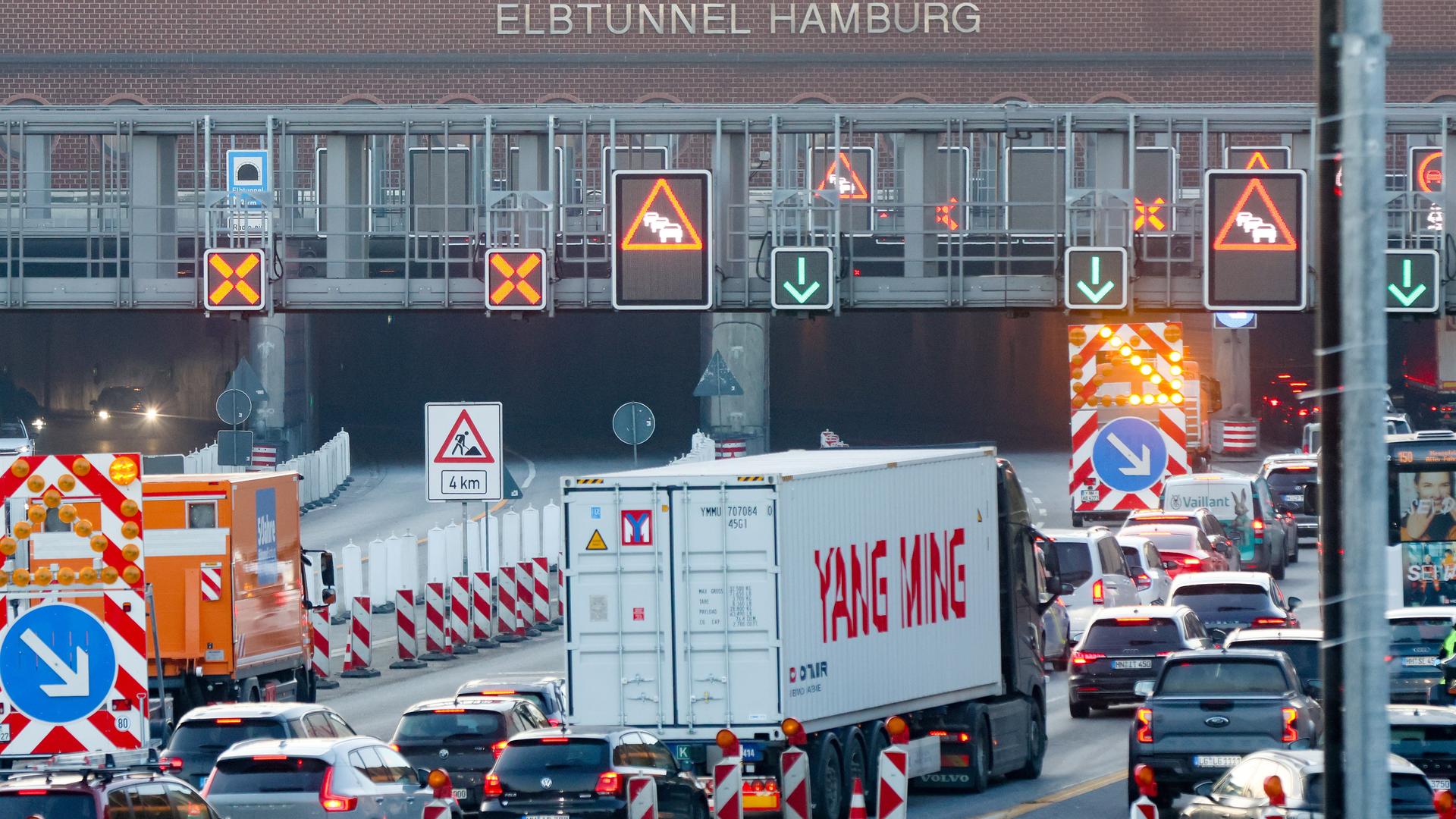 Vue d'ensemble : une file de voitures s'engouffre dans l'ouverture d'un tunnel. Vue d'ensemble : une file de voitures s'engouffre dans l'ouverture d'un tunnel.