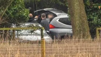 Une image floue de deux voitures et plusieurs personnes près d'un coffre ouvert
