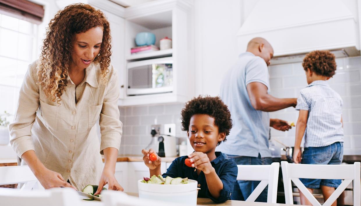 Des parents africains avec leurs enfants préparant des ingrédients pour le dîner.