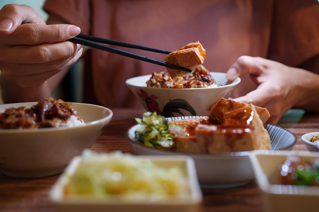 Gros plan sur une jeune fille savourant un plat taïwanais de porc braisé.