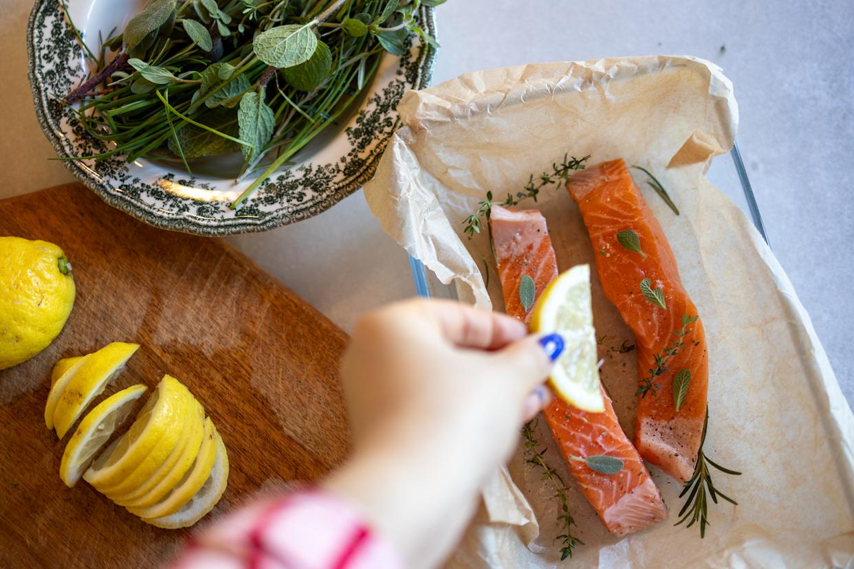 Vue aérienne de steaks de saumon cru décorés d'herbes et de tranches de citron avant cuisson.