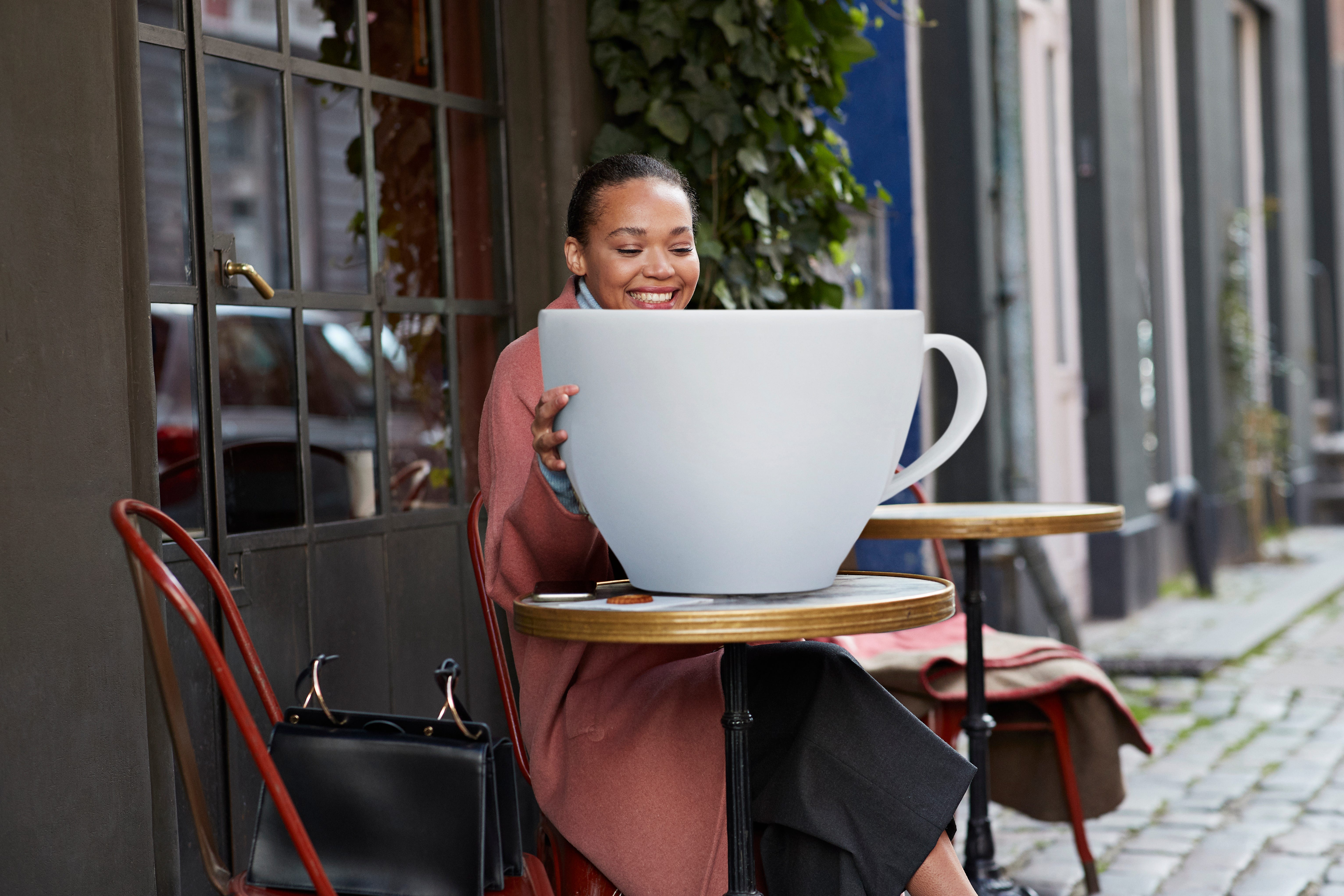 Tasse de café ridiculement grande devant un café