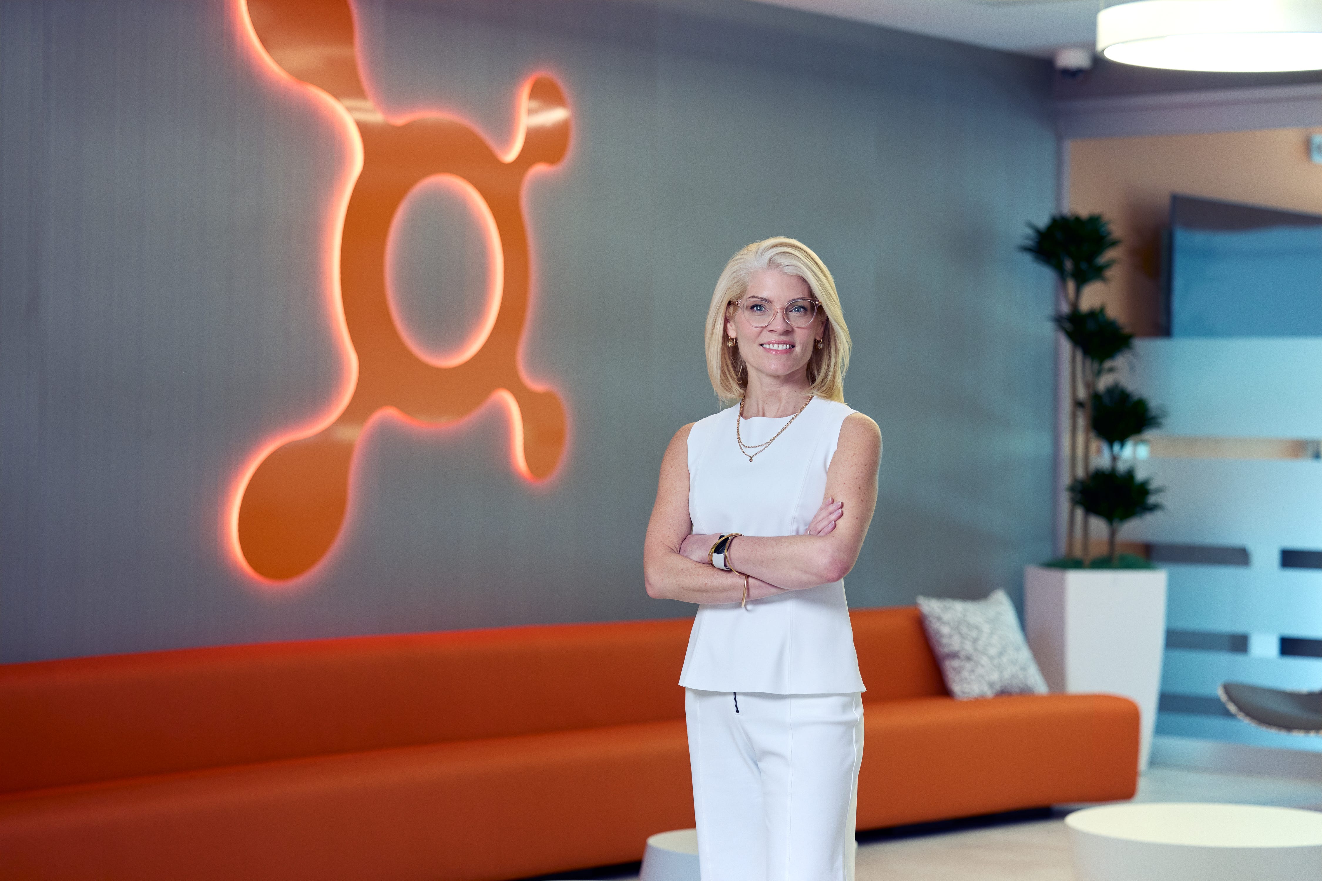 Lauren Cody, présidente d'Orangetheory, dans son bureau avec le logo de la marque derrière elle