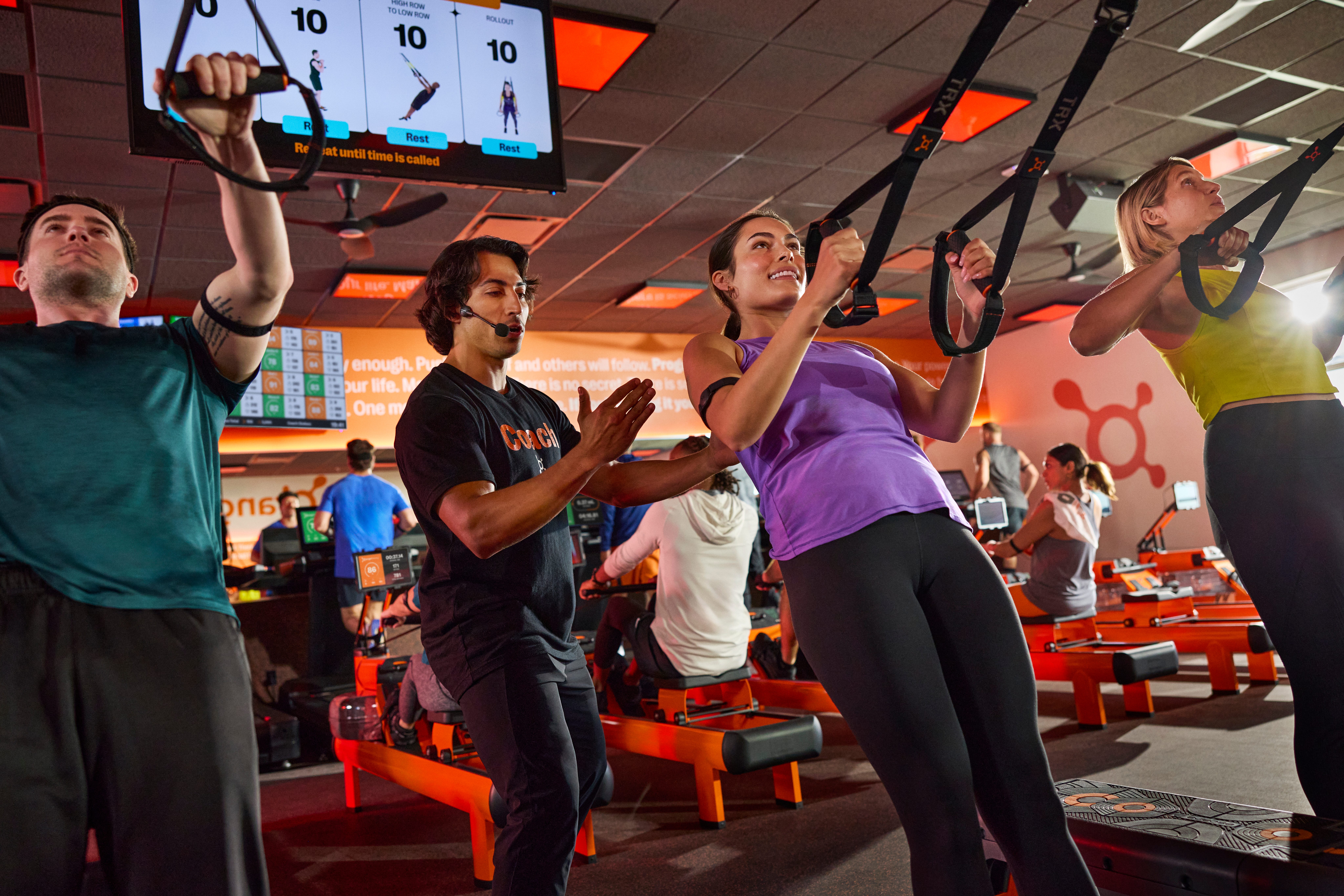 Un cours d'Orangetheory avec des participants effectuant des exercices d'aviron sur TRX