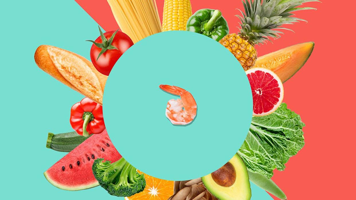 Pain, céréales, fruits et légumes disposés en cercle autour d'une crevette au centre.