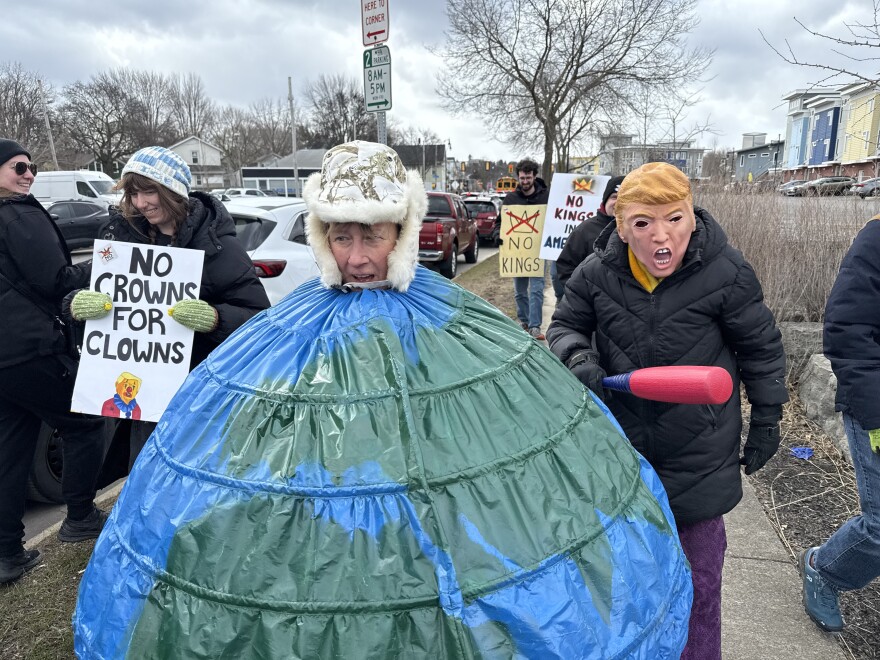 Des artistes de performance à Rochester, Tory Gregory et Janet Lipp, représentent le Président Trump et la planète Terre lors du rassemblement No Kings.