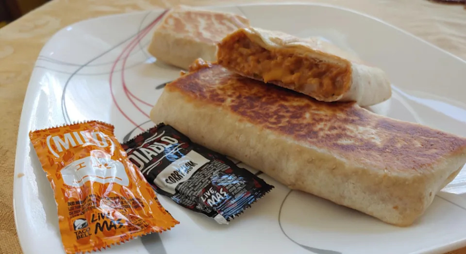 Deux burritos grillés, l'un coupé pour révéler une garniture fromagée et saucée