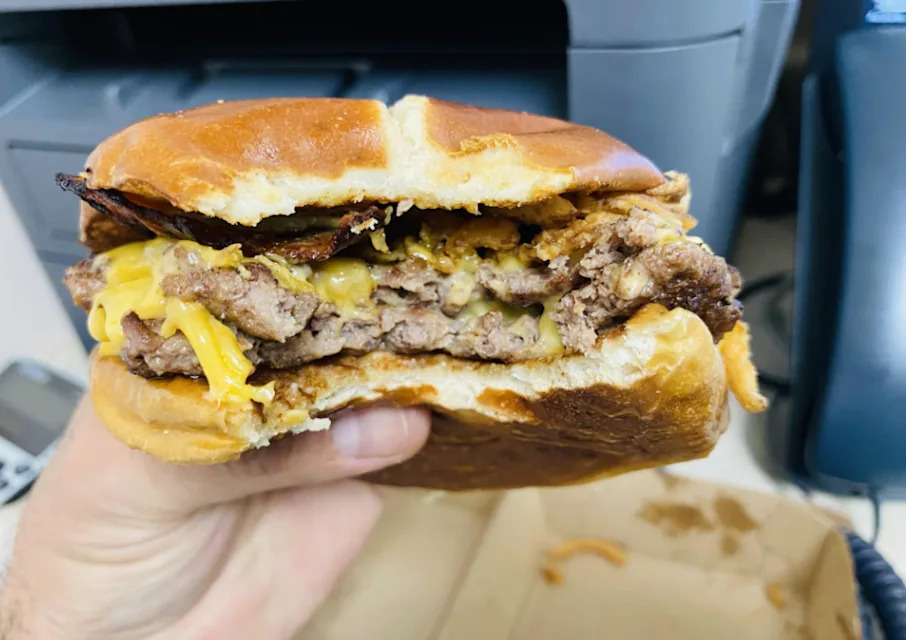 Un cheeseburger avec deux steaks de boeuf et fromage sur un bun grillé
