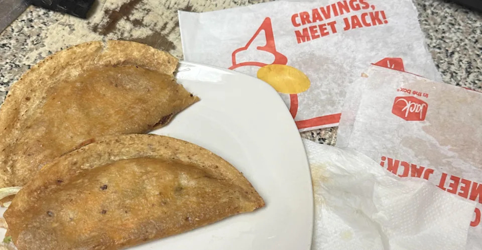Deux tacos remplis de viande sur une assiette, accompagnés de wrappers de la chaîne