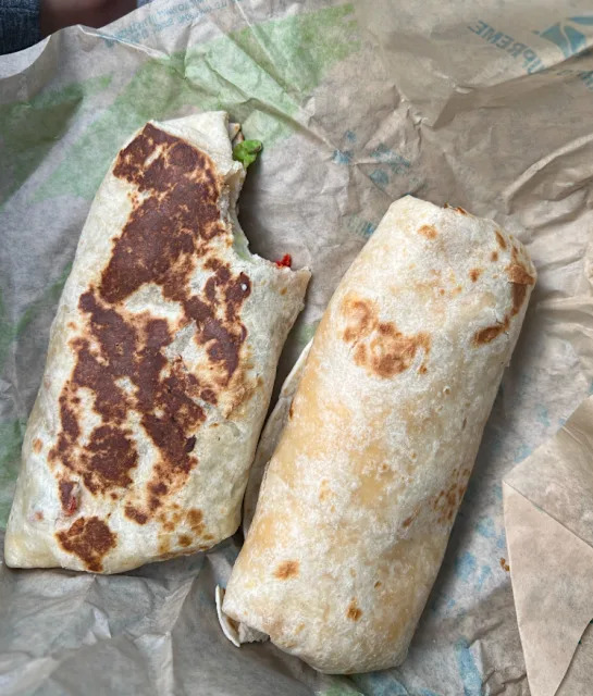 Deux burritos, l'un croqué, tous deux emballés dans des tortillas de farine