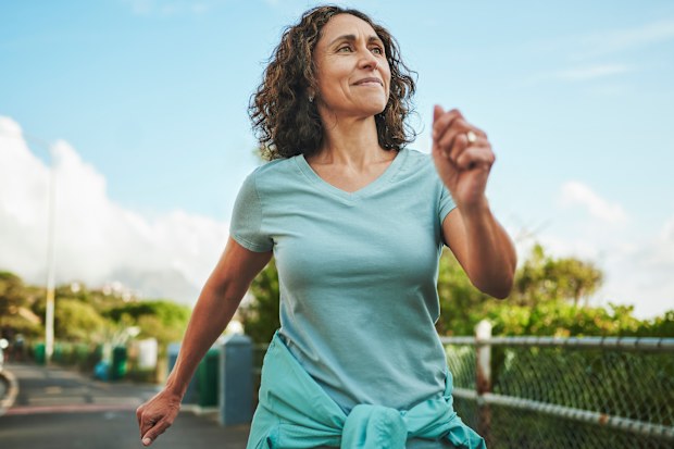 Femme souriante marchant dans un parc.