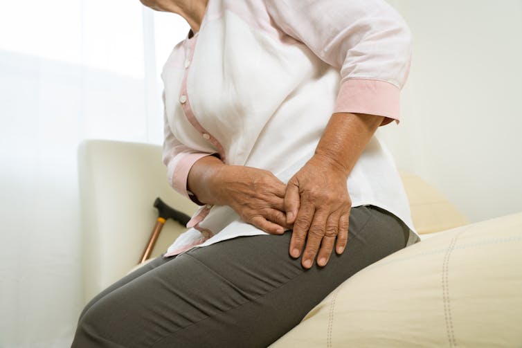 Personne âgée tenant un membre, semblant éprouver de la douleur