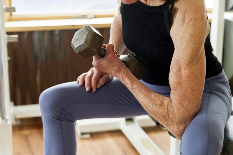 Une femme de 76 ans dans une salle de sport, utilisant un haltère