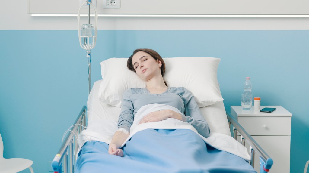 Une jeune patiente allongée dans un lit d'hôpital avec une perfusion.