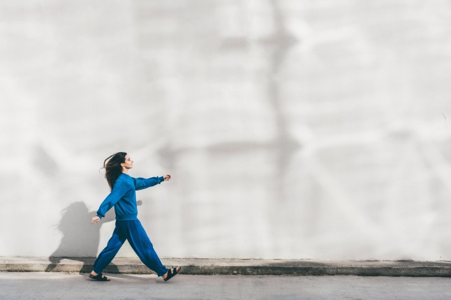 Jeune femme marchant contre un mur.