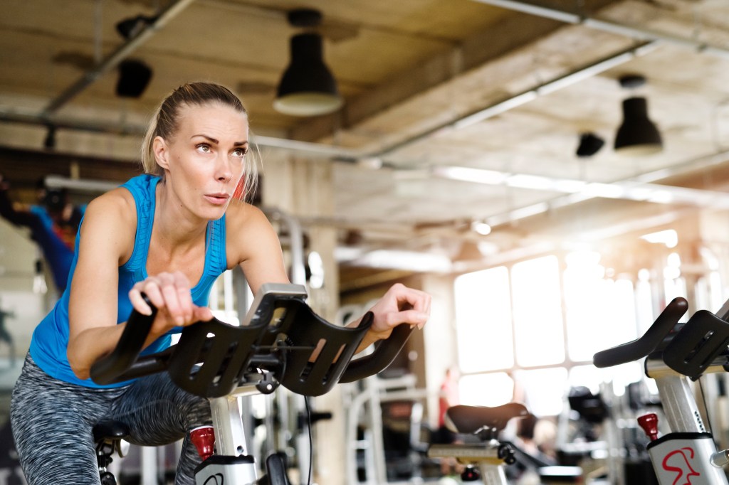 Femme faisant du vélo sur un appareil dans une salle de sport.