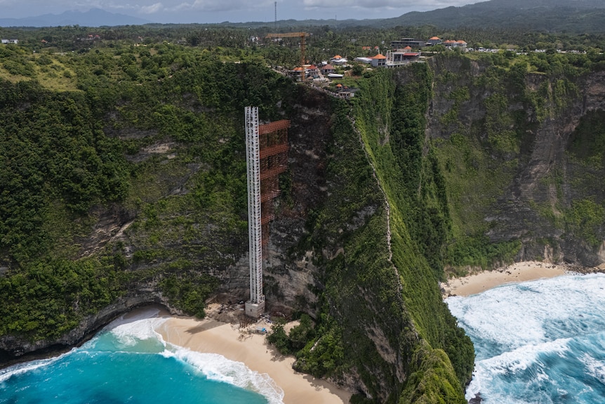 Vue aérienne d'une plage à Bali montrant une tour à côté d'une falaise.