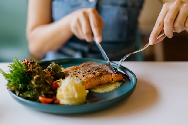 Femme dégustant du saumon et des légumes